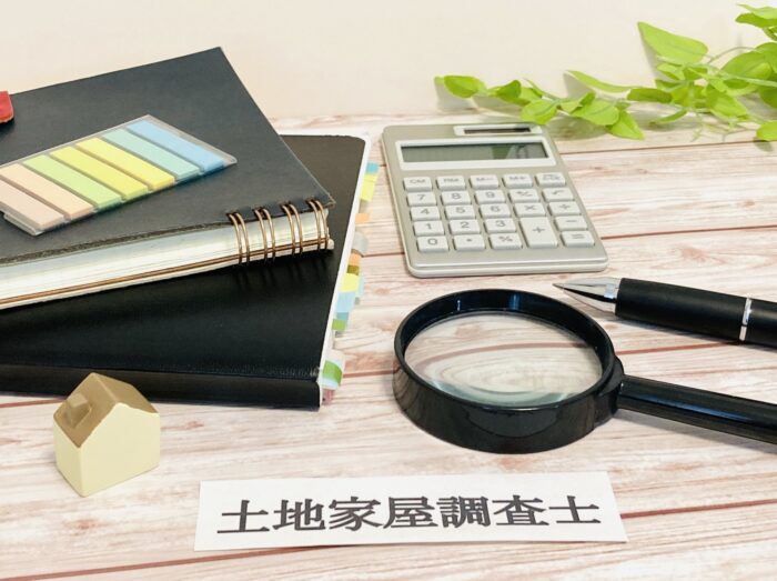 土地家屋調査士のプレートと費用計算を想起させる電卓および虫眼鏡