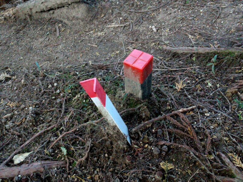 地面から斜めに抜けかけている境界標と残された境界杭